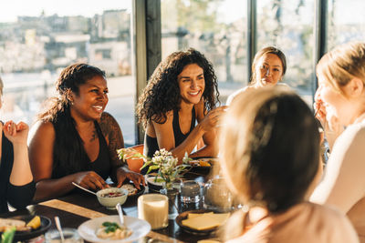 Happy female friends sitting and having breakfast together at retreat center