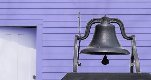 Bell hanging against purple wall