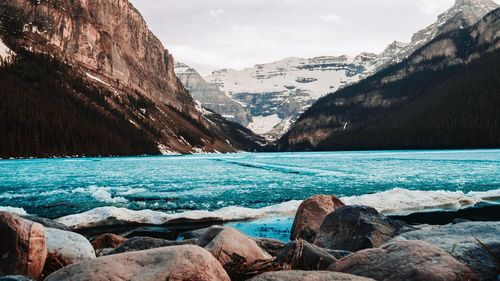 Scenic view of lake by rocks against sky