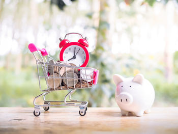 Close-up of coins in miniature shopping cart on table