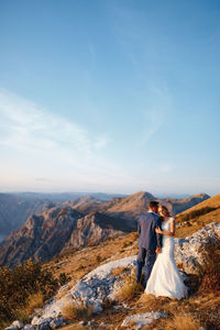 Rear view of couple holding mountain against sky