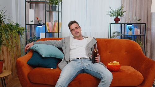 Young woman using phone while sitting on sofa at home