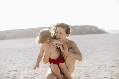 Happy mother with shirtless boy enjoying at beach