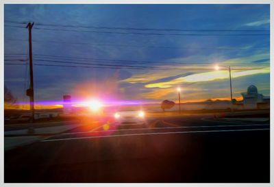 Cars on road against sky during sunset