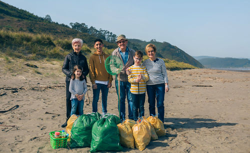 Portrait of happy family standing after cleaning at beach