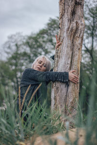 Portrait of woman with arms raised on tree