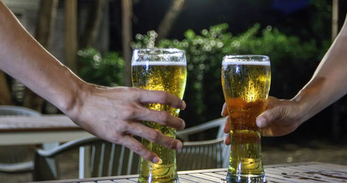 Cropped hands of friends toasting beer glasses