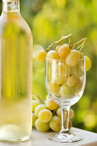 Close-up of wine bottle by grapes filled wineglass on table