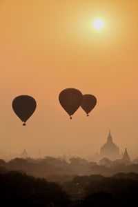 Silhouette hot air balloons against sky during sunset