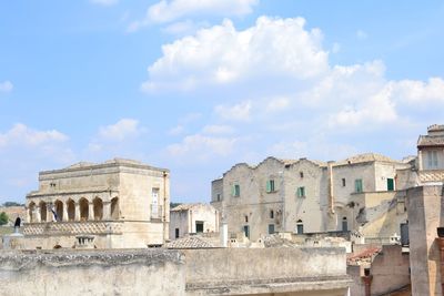 Cliff dwellings at sassi di matera against cloudy sky