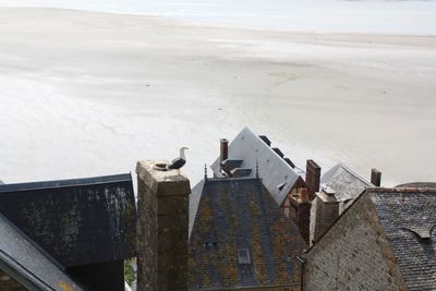 Birds perching on roof against sky