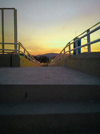 Bridge over road against sky at sunset