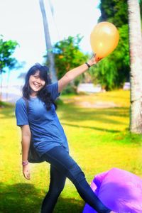 Smiling young woman with balloons at park