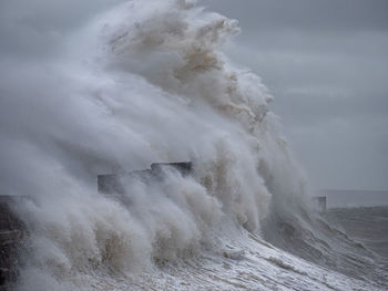 Waves splashing on shore against sky