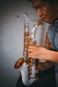 Man playing saxophone against wall