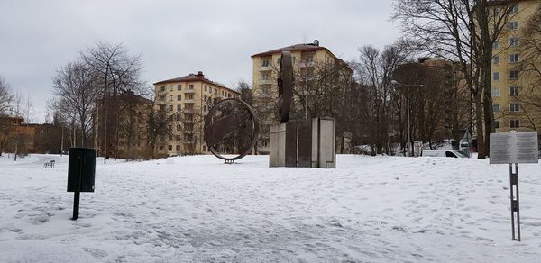 Snow covered field by houses against sky