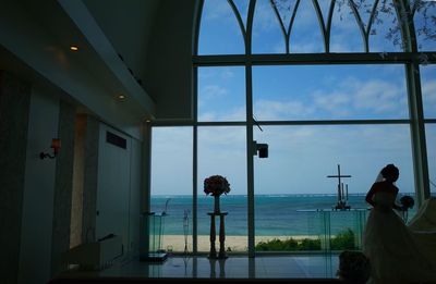 Rear view of people in sea against sky seen through window