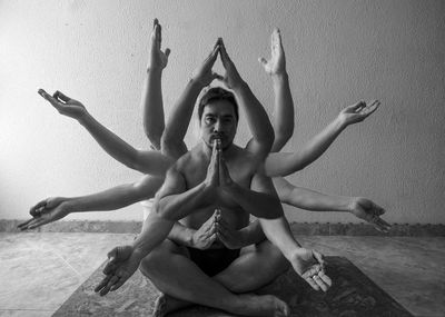 Low angle view of young woman with arms raised against wall