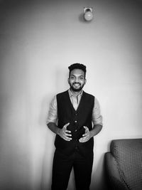Portrait of young man standing against wall