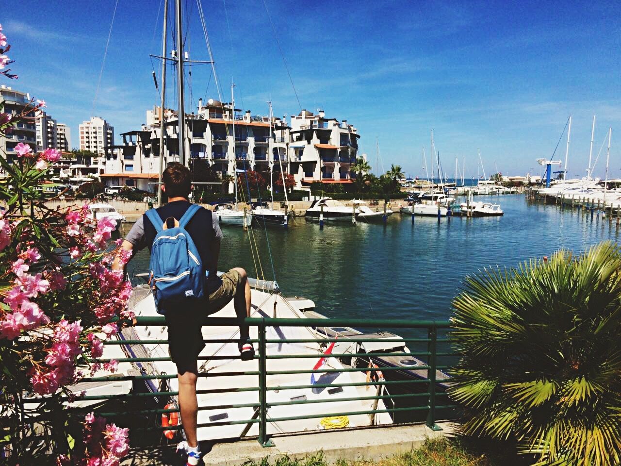 nautical vessel, transportation, moored, building exterior, architecture, water, boat, sky, mode of transport, built structure, travel, casual clothing, sea, blue, travel destinations, sailboat, day, scenics, tourism, vacations, tranquil scene, cloud - sky, tranquility, harbor, in front of, person, hobbies