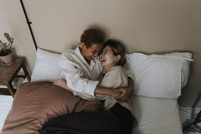 Non-binary couple enjoying with each other while lying on bed at home