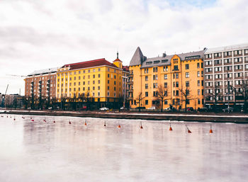 Buildings by river in city against sky