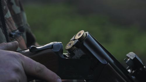 Midsection of man loading shotgun