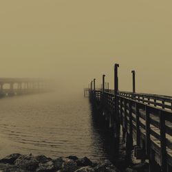 Pier in sea at sunset