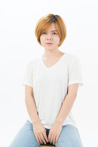 Portrait of teenage girl sitting against white background