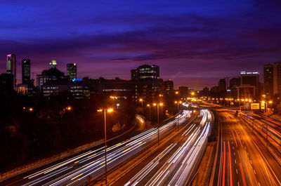 High angle view of light trails on road amidst buildings at night