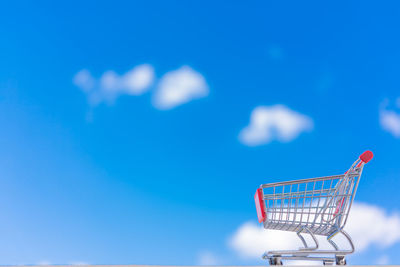 Low angle view of shopping cart against blue sky