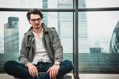 Portrait of young man sitting by window