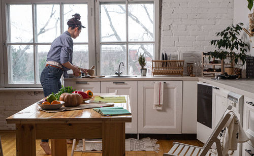 Young and beautiful housewife woman cooking in a white kitchen