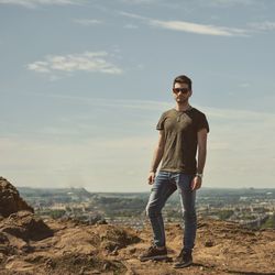 Full length of man wearing sunglasses while standing on mountain against sky