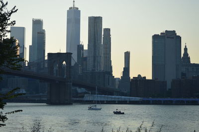 Modern buildings by river against sky in city