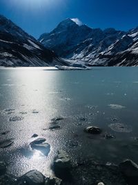 Scenic view of lake by snowcapped mountains against sky