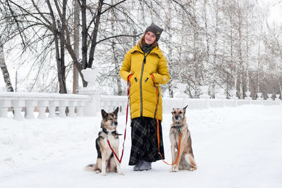Woman walking with dogs on snow covered street