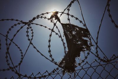 Low angle view of barbed wire fence against clear sky