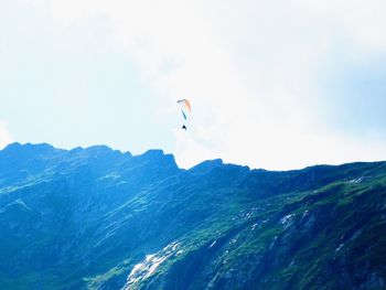 Low angle view of person paragliding against mountain