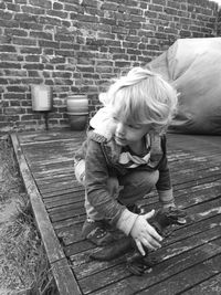 Cute boy holding dinosaur toy while crouching on floorboard