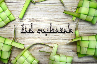 Eid mubarak text with ketupat casing on wooden table