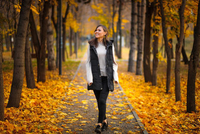 Portrait of woman standing in forest during autumn