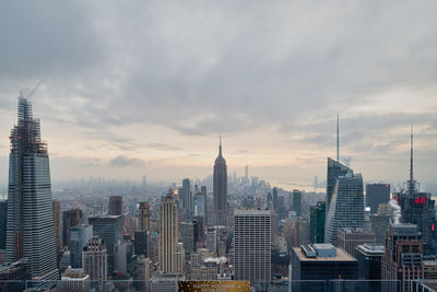 Buildings in city against cloudy sky