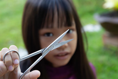 Close-up portrait of girl holding scissor