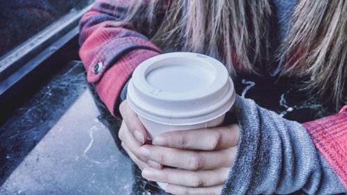 Midsection of woman holding disposable coffee cup