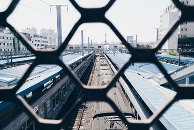 Train at railroad station seen through metal fence