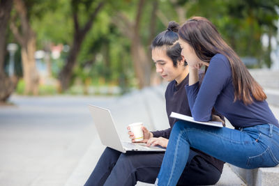 Young woman using mobile phone while sitting outdoors