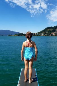 Rear view of woman standing in sea against sky