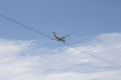 Low angle view of birds on cable against sky