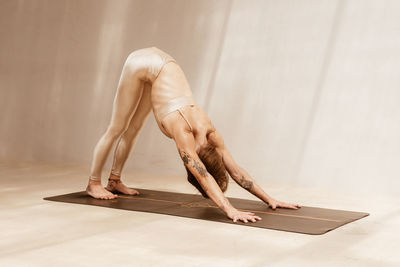 Side view of a woman doing a yoga pose on studio